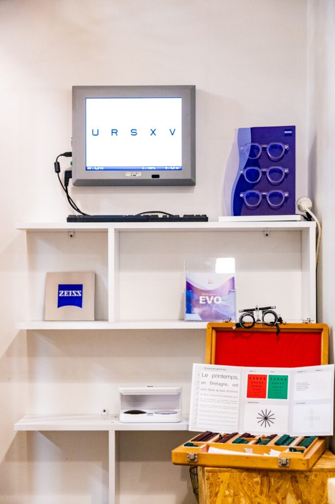 Matériel d'optométrie ZEISS : examen de la vue Équipement d'optométrie Zeiss : écran affichant URSXV, lunettes d'essai et matériel de réfraction sur des étagères blanches.
